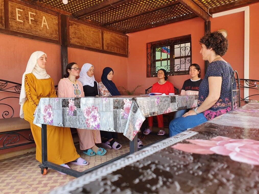 A group of women sitting around a table with their eyes closed.